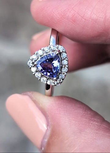 Thumbnail: a modern white gold ring set with a deep rich trillion cut tanzanite which is surrounded by small round white zircons