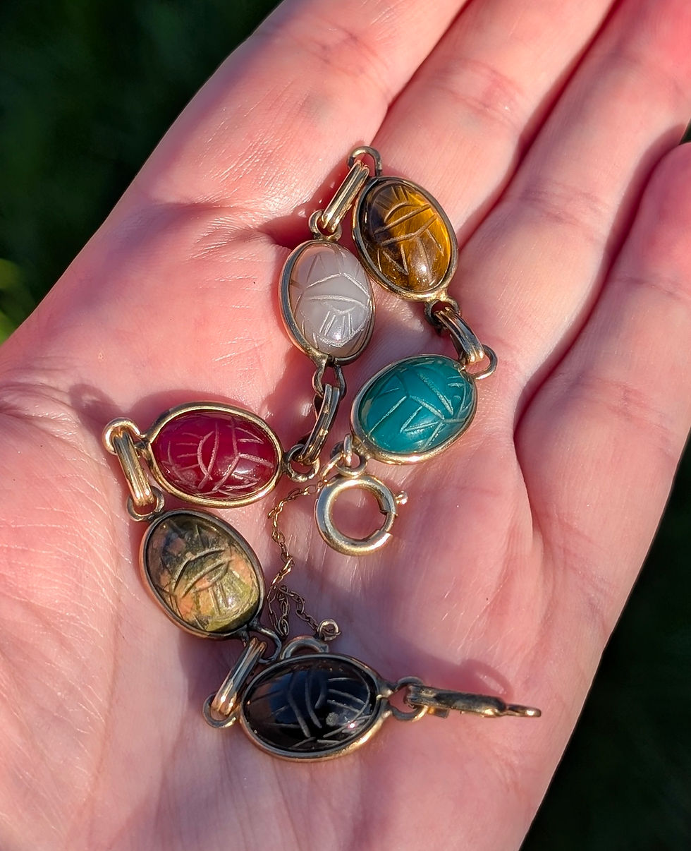 Thumbnail: A vintage yellow gold bracelet with different coloured carved gemstone scarab beetles