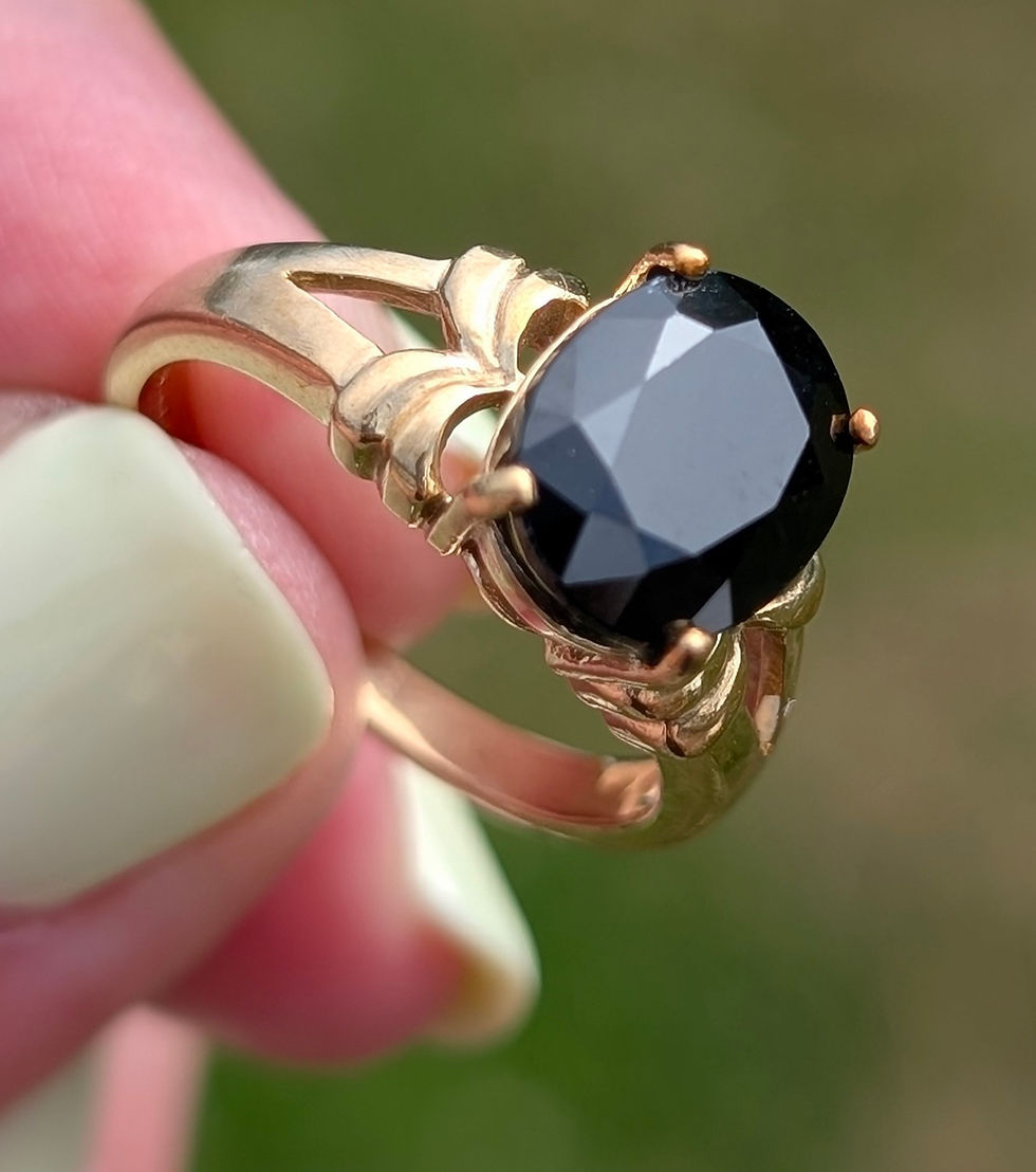 Thumbnail: a large oval facetted black sapphire set into a yellow gold ring