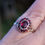 Thumbnail: Antique yellow gold ring with a oval faceted red garnet surrounded by a smaller round halo of red garnets