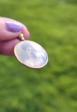 Thumbnail: a round double sided photo locket edged in yellow gold inside an image of an Edwardian lady