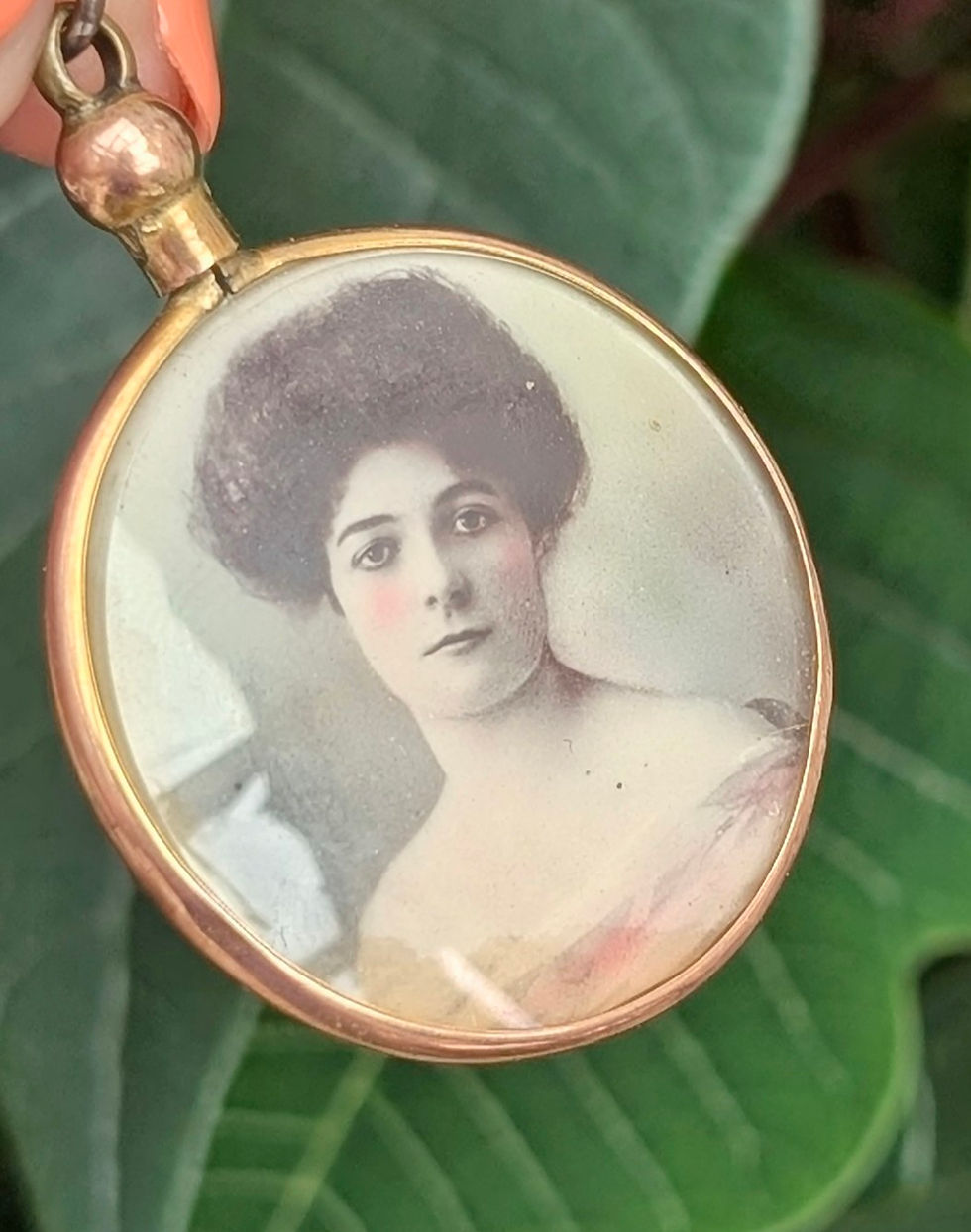 Thumbnail: a round double sided photo locket edged in yellow gold inside an image of an Edwardian lady