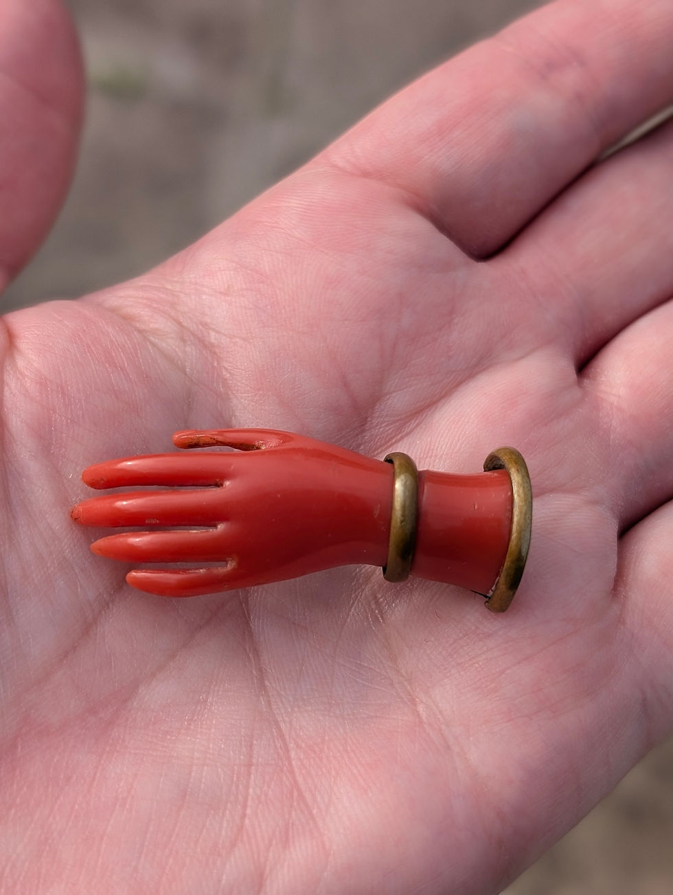 Thumbnail: A Victorian brooch of a red hand with gold bracelets