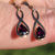Thumbnail: vintage yellow gold dangling earrings with pear shape red garnets set in an infinity shape