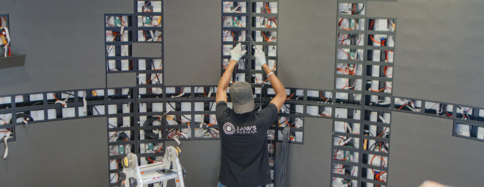 AV technician adjusting LED wall panels on a curved display during installation.