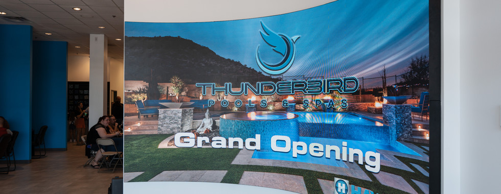 Curved indoor LED screen showing a grand opening graphic in a commercial environment.