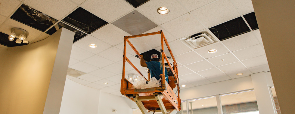 Installer on a lift mounting ceiling infrastructure for an LED wall and AV system