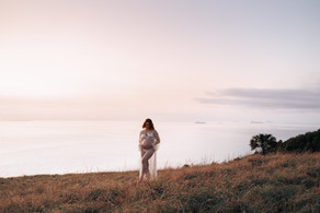 Pregnant mother in lace gown standing on grassy lookout in Yeppoon