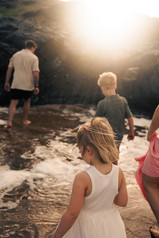 family walking through water at Emu Park beach, taken during a family photoshoot with Sarah Joy, a Rockhampton Family Photographer