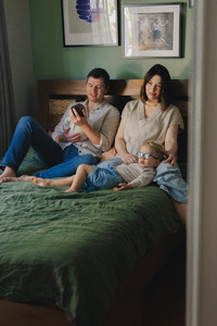 Family sitting on their family bed with newborn in arms during newborn photgraphy session Rockhampton