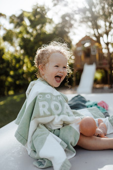 Young girl smiling in towel on top of table during in home family photography session in Rockhampton with Sarah Joy, a Rockhampton family photographer