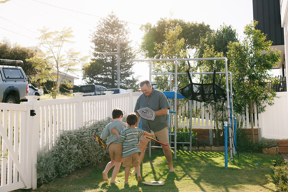 Children holding toy swords, laughing and running around Dad during a candid family moment.