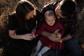 Close-up of toddler and mum and dad laughing during golden hour session