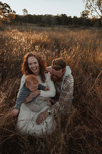 Rockhampton family smiling and laughing in candid photo in Rockhampton field at sunset