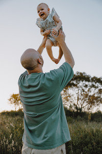Dad throwing his daughter in the air while she laughs 