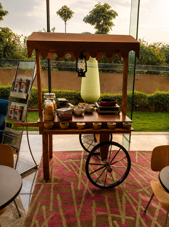 Outdoor rustic wooden food cart under a wooden roof canopy setup in a hotel garden lawn.