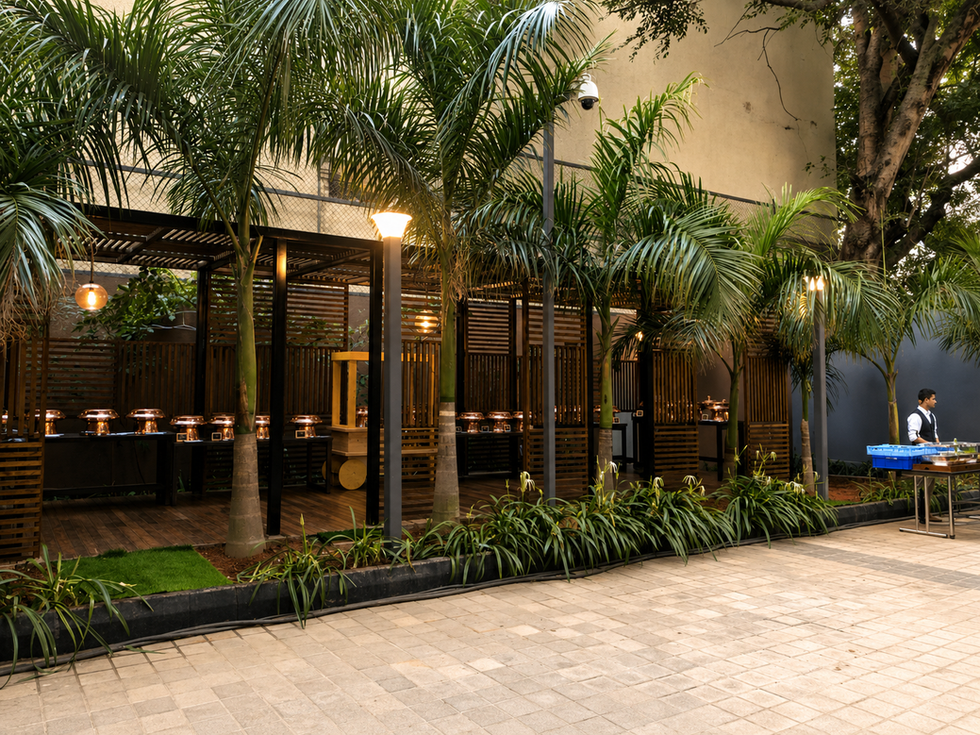 Wooden slat pergola outdoor dining pavilion surrounded by palm trees with warm ambient lighting.