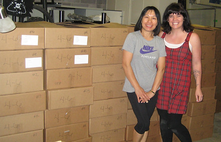 Two adults standing next to stacks of boxes.