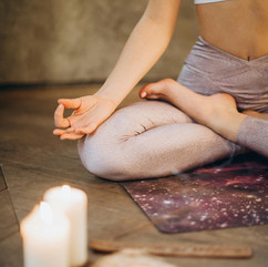 Woman meditating, candles nearby