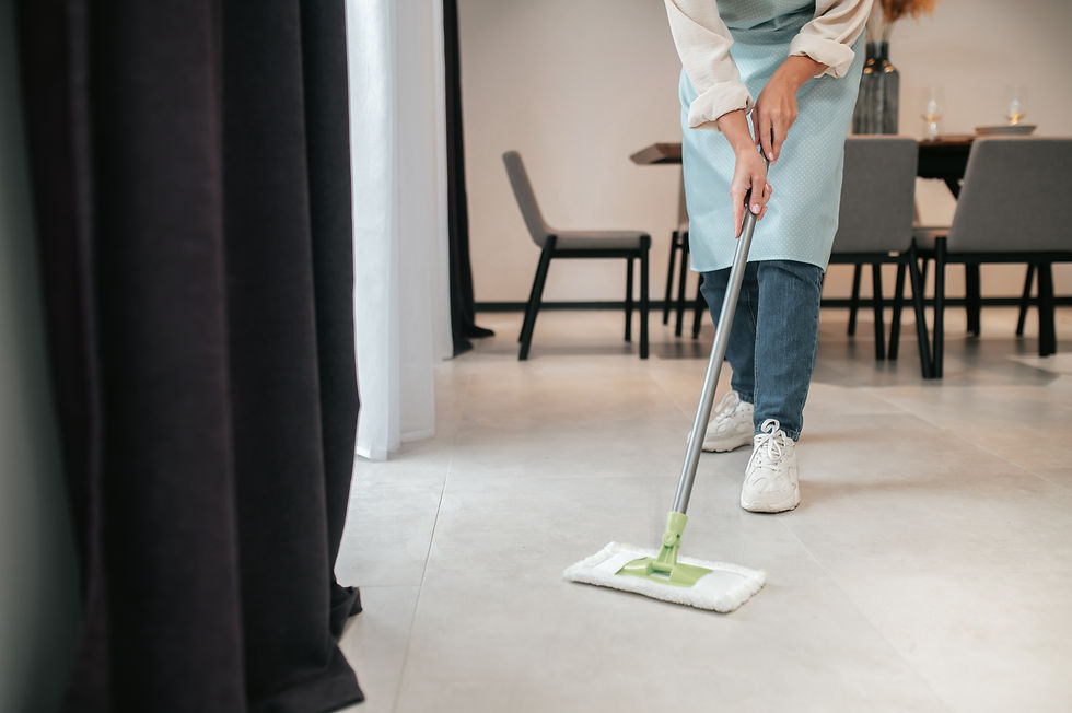 Persoon moppt de tegelvloer in een eetkamer met stoelen en tafel