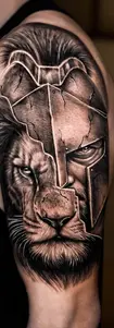 Realism style black and grey shoulder tattoo featuring a detailed Spartan warrior helmet and a roaring lion, made in Antalya.