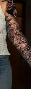 A complex black and grey full sleeve tattoo in Japanese realism style, featuring a Hannya mask, pagoda, and lotuses, created in Tattoo Factory Antalya.