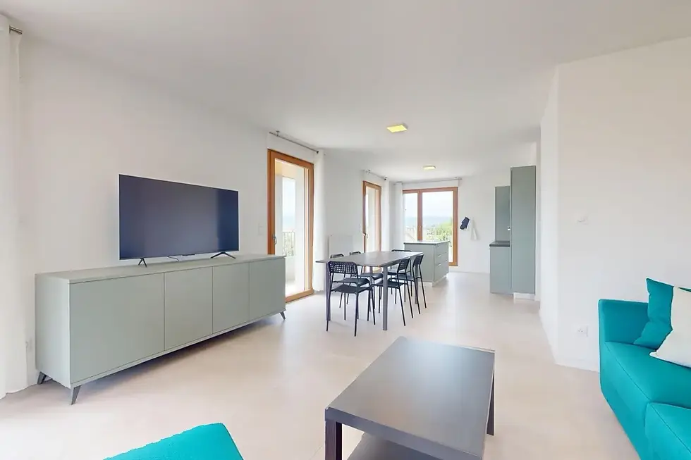 Salon lumineux avec canapé turquoise, coin repas et cuisine ouverte, de la colocation Solar à Ambilly.