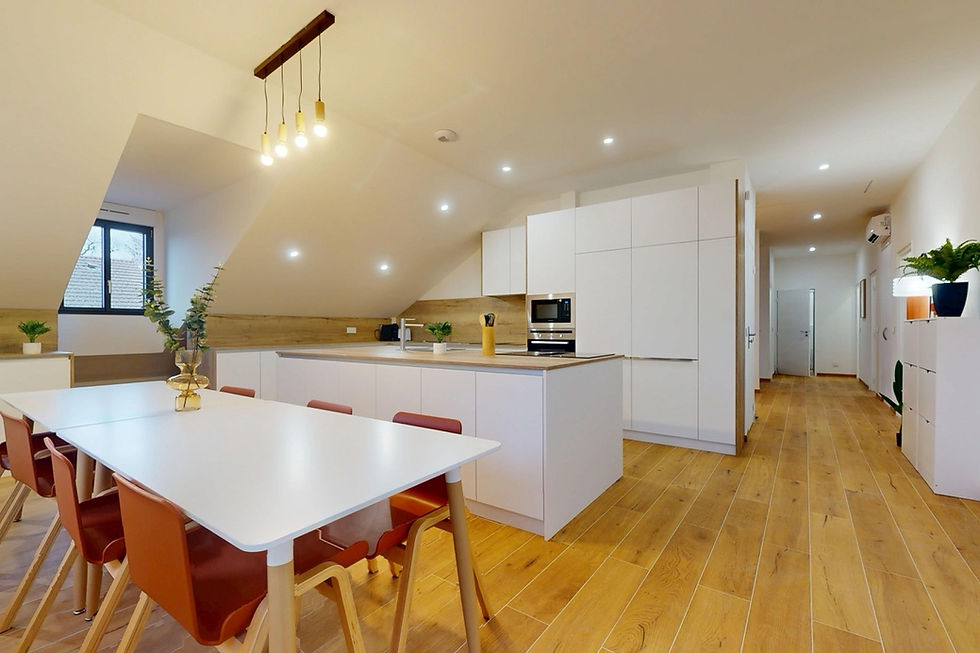 Cuisine ouverte moderne avec îlot blanc, salle à manger conviviale et parquet clair, au cœur de la colocation Kumo à Saint-Genis-Pouilly.