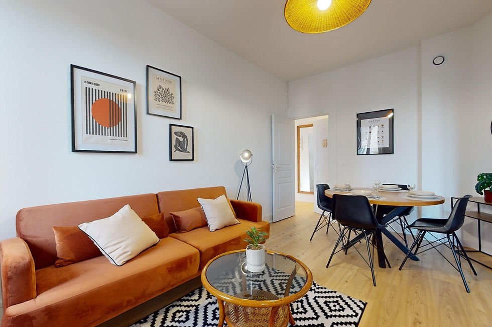 Salon chaleureux avec canapé terracotta, table basse en rotin et coin repas noir moderne. Colocation Clyde à Annemasse.