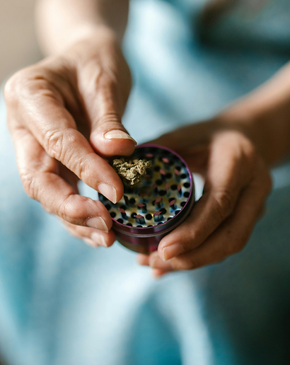 Hands using a grinder to prepare cannabis