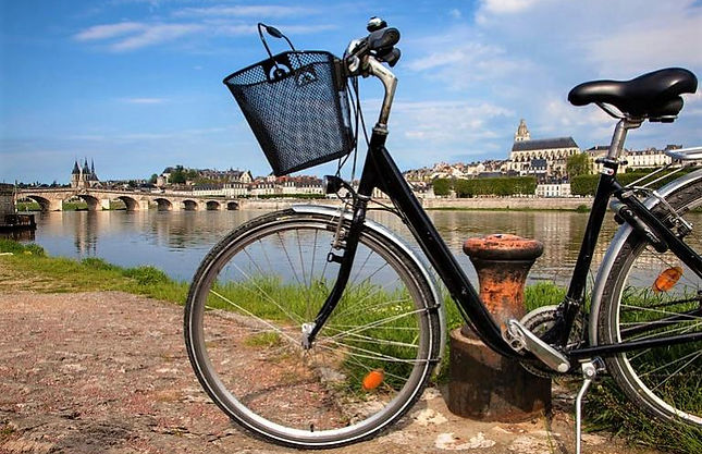 Bicycle with a basket on the front with the Loire river and bridge in the background