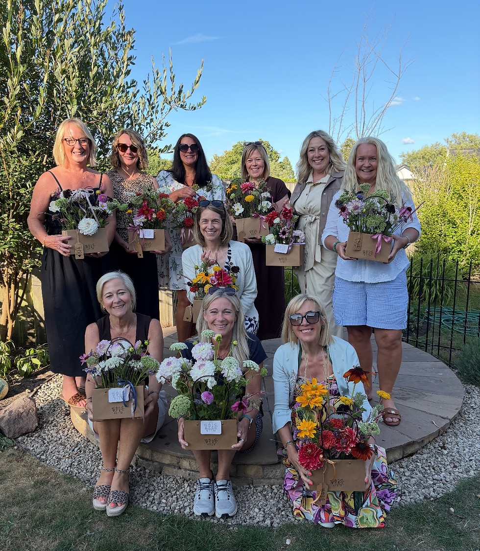 Group of smiling women outdoors holding colourful flower arrangements in boxes