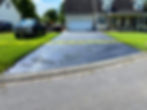 The same residential driveway immediately after sealcoating, freshly sealed and taped off to cure