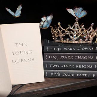 The Young Queens next to a stack of the rest of the Three Dark Crowns series. There's a crown on top of the stack and butterflies flying around