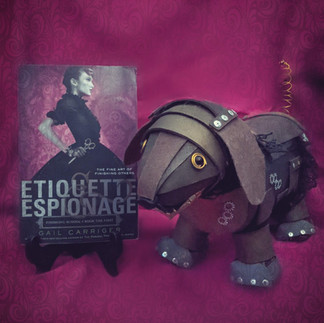 Etiquette and Espionage next to a steampunk weenie dog