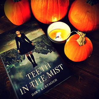 Teeth In the Mist book next to pumpkins and a candle