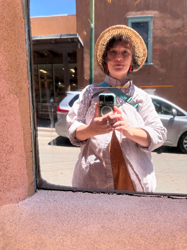 a selfie reflection of Cat, wearing a straw hat, ready to help out!