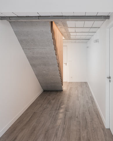 Architecte intérieur Versailles couloir sous-sol Bougival : escalier béton brut garde-corps bois, parquet bois, murs blanc, lumière naturelle, circulation optimisée - Cabinet Antoine de Gironde 10 rue Fontenay Versailles aménagement sous-sols extension