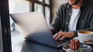 Man using laptop in cafe.