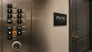 Modern luxury apartment hallway featuring an elevator button panel beside a penthouse apartment door labeled PH10, highlighting the subtle details that shape premium customer experiences.