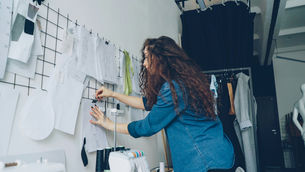 Designer reviewing sketches and concepts pinned to a studio wall, thoughtfully evaluating ideas and refining creative decisions during the design process.