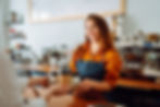 Female barista handing coffee cups in a tray to a customer across a countertop.