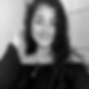 Foto em preto e branco de uma mulher branca, cabelos ondulados pretos jogados à esquerda sobre o ombro, sorridente, olhos escuros, pequenos e redondos. Veste camiseta preta. Fundo branco. Fim da descrição.