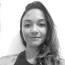 Foto em preto e branco, close de rosto de uma mulher branca, cabelos castanhos lisos, abaixo dos ombros, penteados para o lado direito da tela. Fundo branco. Fim da descrição