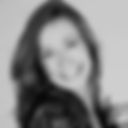 "Foto em preto e branco de close do rosto de uma mulher branca, cabelos louros, lisos, um pouco abaixo dos ombros. Ela está sorridente.
O corpo virado em perfil à direita e o rosto posicionado de frente para a tela. Fundo branco. Fim da descrição."