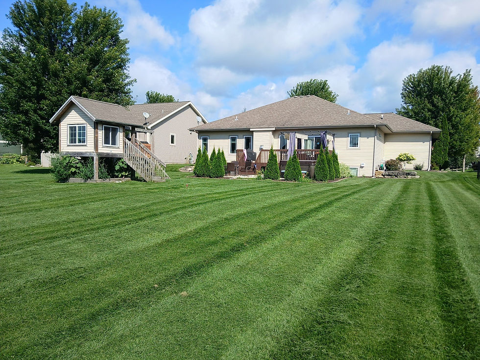 A striped, freshly mowed back lawn behind a ranch home