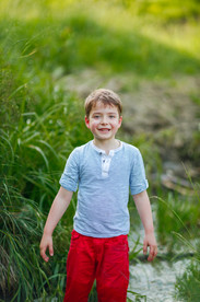 Portret de băiețel vesel, ce se joacă în apa unui pârâu.