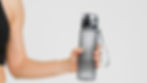 Arm van sportieve vrouw met waterfles in de hand.