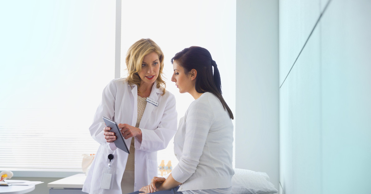 A person talking with their GP in a consultation room, both looking at notes together, conveying a collaborative conversation.