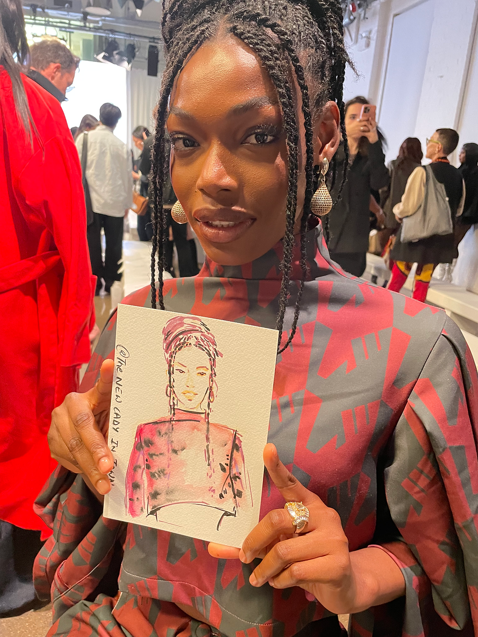 Woman holding a hand-drawn sketch of herself at the london fashion week by the lady in town